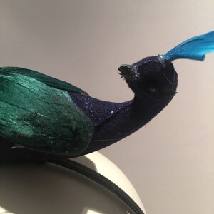 May include: A peacock headband with a blue feather, green and blue velvet, and a black headband.