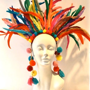May include: A colorful feather headdress with a headband and dangling pom-poms. The headdress is made of feathers in various colors, including red, orange, yellow, green, blue, and purple. The pom-poms are also in various colors, including red, orange, yellow, green, blue, and pink.