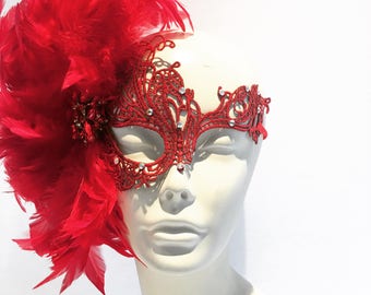 May include: A red lace masquerade mask with rhinestones and a red feather accent.