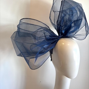 May include: A large navy blue tulle bow headband. The bow is made of multiple layers of tulle and is very full. The headband is simple and plain.