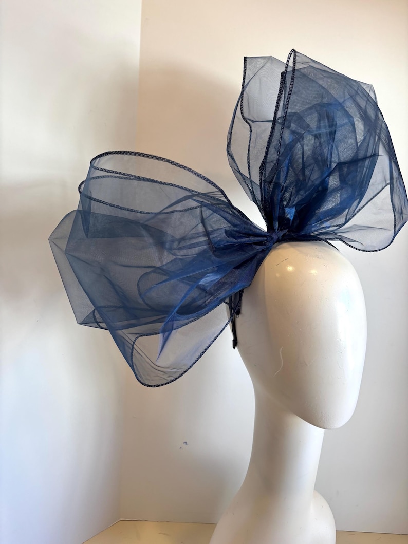 May include: A large navy blue tulle bow headband. The bow is made of multiple layers of tulle and is very full. The headband is simple and plain.