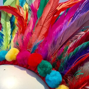 May include: A colorful feather headdress with a red base and pom-poms in various colors, including yellow, blue, green, and pink.