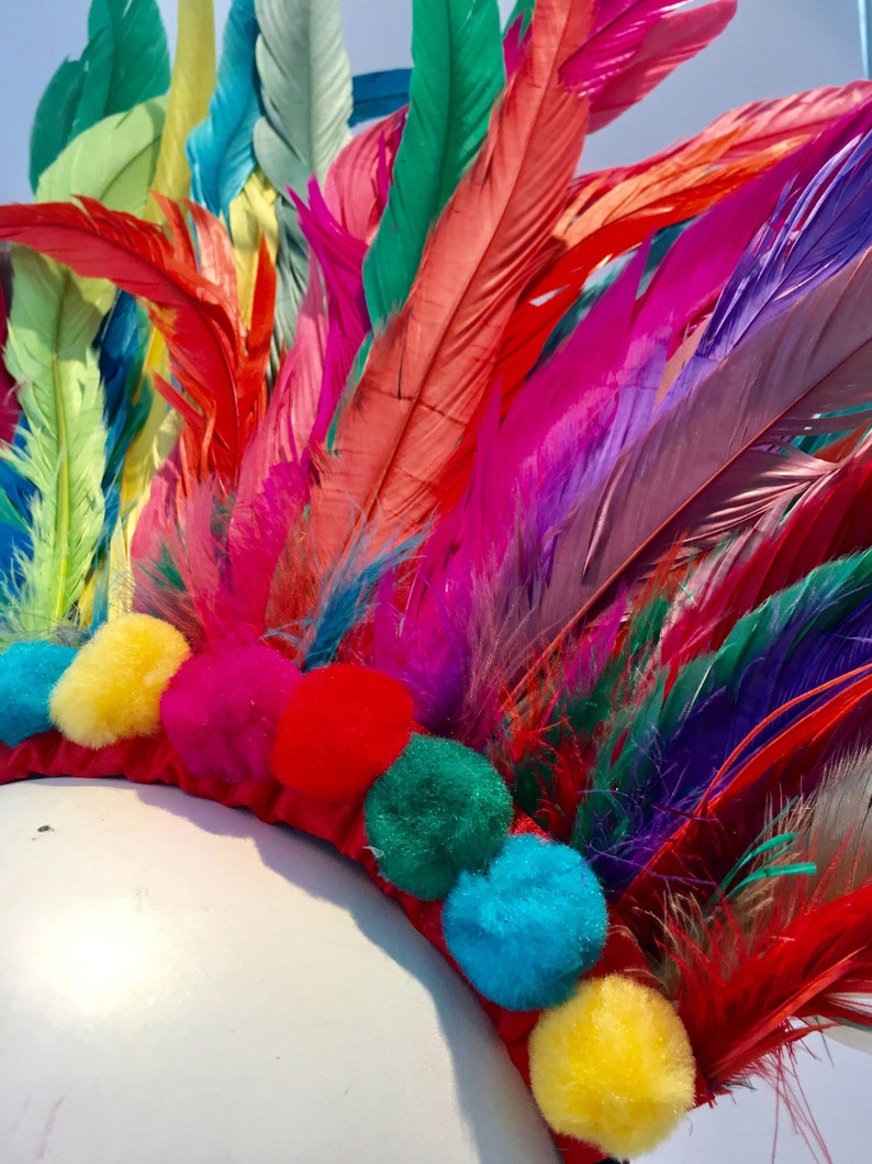 May include: A colorful feather headdress with a red base and pom-poms in various colors, including yellow, blue, green, and pink.