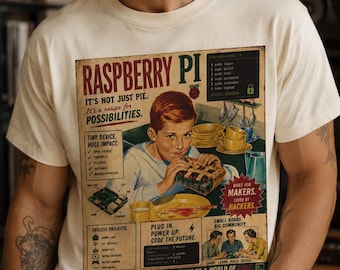 May include: A cream-colored short-sleeve t-shirt featuring a vintage-style graphic print. The design includes a young person eating a pie made of circuit boards, with text reading Raspberry Pi, It's not just pie. It's a recipe for possibilities.