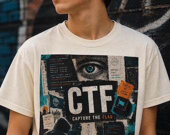 May include: A cream-colored t-shirt featuring a graphic print with the text CTF CAPTURE THE FLAG. The design includes a human eye, a hooded figure, computer code, a skull flag, and the phrases TRUST NO INPUT, GAME ON, and ACCESS IS EARNED NOT GIVEN.
