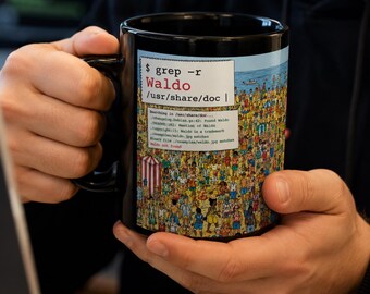 May include: A black ceramic mug featuring a graphic print of a crowded beach scene with a white text box overlay. The text reads $ grep -r Waldo /usr/share/doc followed by a list of file paths and the final line stating Waldo not found.