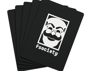 May include: A stack of black rectangular playing cards featuring a white graphic of a smiling mask inside a rectangular border. Below the mask, the text fsociety is printed in a white pixelated font. The cards are fanned out slightly.