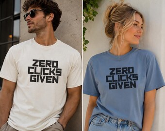May include: A short-sleeved crew neck t-shirt available in off-white or dusty blue, featuring the text "ZERO CLICKS GIVEN" printed in a bold, black, block-style sans-serif font across the center of the chest on both color variations.