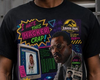 May include: A black t-shirt featuring a graphic print of Dennis Nedry from Jurassic Park. The design includes a computer monitor, a keyboard, a Jurassic Park ID badge, and text that reads I HATE THIS HACKER CRAP, DANGER 10,000 VOLTS, and T.REX DETECTED.