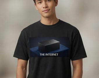 May include: A black short-sleeve t-shirt featuring a rectangular graphic print on the chest. The graphic depicts a small black box resting on a blue surface with the white text THE INTERNET printed directly underneath the box image.