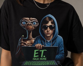 May include: A black t-shirt featuring a graphic print of the character E.T. wearing glasses and a person in a blue hoodie wearing sunglasses. They are both positioned behind a laptop with a green keyboard and the text E.T. HACK HOME on the screen.