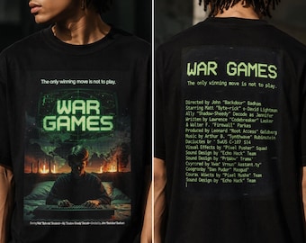 May include: A black t-shirt featuring a War Games movie poster graphic on the front with a person at a computer and the text The only winning move is not to play. The back displays the title War Games and a list of credits in green text.