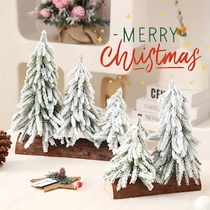 May include: A set of five artificial Christmas trees with green needles covered in white flocking, each mounted on a natural brown wooden log base. The text Merry Christmas is displayed in green and red script above the trees.