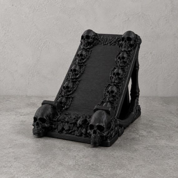 A hand-cast matte black resin skull that moonlights as a phone stand — gothic desk decor that actually does something useful.