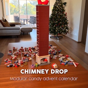 Puede incluir: Una estructura alta de chimenea con patrón de ladrillo rojo y una figura de Santa Claus atrapada boca abajo en la parte superior. La base tiene una abertura de chimenea. Texto: CHIMNEY DROP Modular candy advent calendar. Dulces esparcidos.