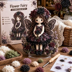 Peut inclure: Un kit d'art textile 3D Flower Fairy représentant une poupée aux cheveux bruns, couronnée de fleurs, vêtue d'une robe sombre avec des ailes. Le kit comprend un outil en bois, des touffes de tissu colorées et une fiche d'instructions illustrée.