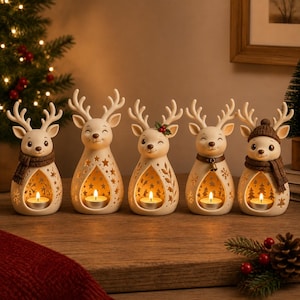 May include: Five cream-colored ceramic reindeer figurines, each featuring a hollow center containing a lit tea light candle. The reindeer have varied details including brown knit scarves, a small bell, a holly sprig, and a brown knit hat.