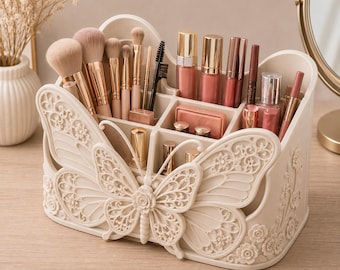 Può includere: Un organizer per trucchi in plastica color crema con un intricato design a farfalla sul davanti e motivi floreali in rilievo sui lati. Il contenitore presenta diversi scomparti per pennelli da trucco, rossetti e ciprie compatte.