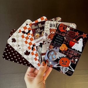 Op de afbeelding: Een set van vijf rechthoekige kaarten met Halloween- en herfstthema's. De ontwerpen bevatten oranje en witte ruitpatronen met vleermuizen en bladeren, een teddybeer en een collage met een geest en een skelet met een pompoenhoofd.