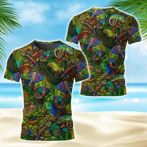 Puede incluir: Una camiseta de manga corta con un estampado integral de camaleones coloridos y follaje tropical. El diseño incluye varios camaleones en tonos morados, azules, verdes y naranjas, sobre un fondo denso de hojas verdes.