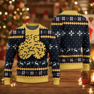May include: A long-sleeve crew neck jumper in navy blue and yellow featuring a repeating pattern of white snowflakes and white reindeer. The front displays a large, central yellow graphic of two rounded, textured shapes with black outlines.