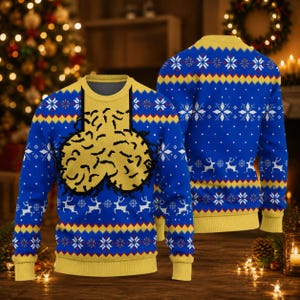 May include: A long-sleeved knit jumper in royal blue and yellow featuring a repeating pattern of white snowflakes and white reindeer. The front displays a large, central yellow graphic with black outlines, while the collar, cuffs, and hem are yellow.