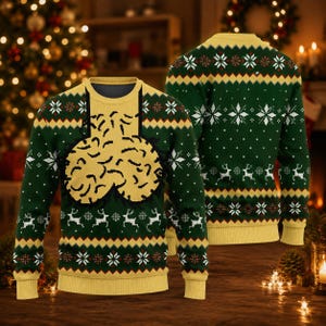 May include: A long-sleeved crew neck jumper in dark green and yellow featuring a repeating pattern of white snowflakes and reindeer. The front displays a large, central yellow graphic of two rounded, textured shapes with black outlines.