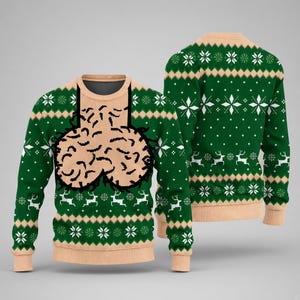 May include: A green long-sleeve jumper featuring a beige and black graphic of testicles on the front. The garment includes a repeating pattern of white snowflakes and white reindeer silhouettes, with beige ribbed cuffs, collar, and hem.