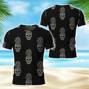 May include: A black short-sleeve t-shirt featuring an all-over repeating pattern of white pineapple-shaped skulls. The design displays the front and back views of the garment, showcasing the crew neck and the consistent graphic print throughout.