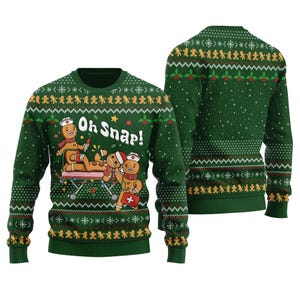May include: A dark green long-sleeve jumper featuring a festive knit pattern with gingerbread characters dressed as medical staff. One gingerbread person lies on a gurney while another stands nearby with a first aid kit. Text reads Oh Snap!