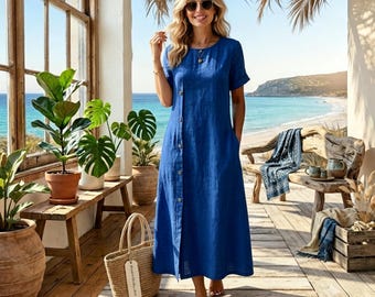 May include: A solid royal blue midi dress with short sleeves, a round neckline, and a vertical row of buttons running down the front. The dress features a relaxed fit and is worn with dark sunglasses and a simple gold necklace on a chain.
