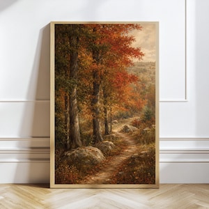 Può includere: Una stampa artistica da parete incorniciata verticalmente che raffigura un dipinto paesaggistico di un sentiero sterrato che si snoda attraverso un bosco in autunno. La scena presenta alberi alti con fogliame arancione e rosso, rocce grigie e un cielo.