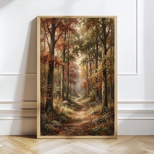 May include: A vertical rectangular framed wall art print depicting a forest path during autumn. The scene features tall trees with foliage in shades of orange, red, and green, with a dirt trail winding through the center past scattered rocks.
