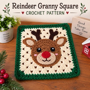Könnte beinhalten: Ein quadratisches Häkelstück mit einem Rentiergesicht mit roter Nase, dunkelbraunem Geweih und schwarzen Augen, zentriert auf einem cremefarbenen Granny Square mit dunkelgrünem Rand. Der Text Reindeer Granny Square CROCHET PATTERN ist sichtbar.