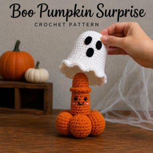 Może przedstawiać: Wzór szydełkowy zatytułowany Boo Pumpkin Surprise przedstawiający białego ducha z czarnymi oczami i ustami, który jest podnoszony, aby odsłonić pomarańczową dynię z uśmiechniętą buzią, czarnymi oczami i różowymi policzkami, wykonany z włóczki.