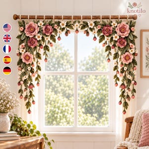 May include: A crochet window valance featuring large pink and mauve flowers, small white blossoms, and dark green leaves. The floral arrangement is suspended from a wooden rod with loops, creating a decorative border across the top of the window.
