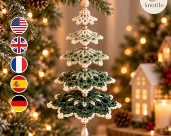May include: A hanging Christmas tree ornament crafted from crocheted yarn in shades of cream, sage green, and dark forest green. The tiered design features five layers separated by small gold-toned beads, with a cream-coloured bead at the top.