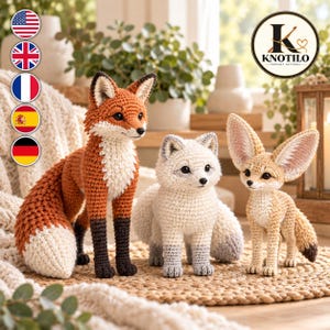 May include: Three crocheted fox figures: a large orange and white fox with black legs, a smaller white and grey arctic fox, and a tan fennec fox with large ears. The figures feature detailed stitching and dark eyes. A logo with the text KNOTILO is visible.