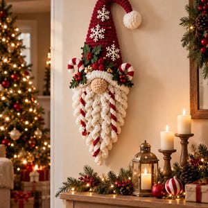 May include: A wall-hanging crochet gnome decoration featuring a tall red pointed hat with white snowflake appliques and a white pom-pom. The gnome has a beige nose, green holly leaves with red berries, candy cane accents, and a long white beard.