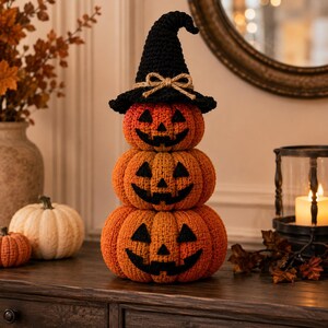 Peut inclure: Un trio empilé de citrouilles orange crochetées avec des visages de jack-o'-lantern en feutre noir. La citrouille du haut porte un chapeau de sorcière noir crocheté orné d'un petit nœud en ficelle beige. Les citrouilles forment une figurine.