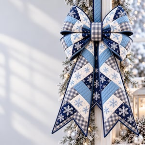 Puede incluir: Un gran lazo de tela acolchada con un diseño de patchwork de cuadrados en azul marino, azul claro y blanco. El patrón incluye intrincados motivos de copos de nieve blancos y un estampado de cuadros vichy en gris y blanco, con un nudo central.