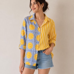 Puede incluir: Una camisa de botones con un diseño dividido, con un lado que muestra un patrón de cuadrícula azul y blanco con rodajas de limón amarillas y el otro lado con rayas verticales amarillas y blancas, combinado con pantalones cortos de mezclilla.