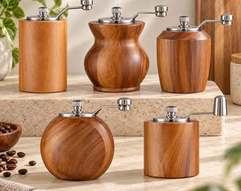 Könnte beinhalten: Ein Set aus fünf hölzernen Gewürzmühlen mit silberfarbenen Metallkurbeln. Das Set umfasst verschiedene Formen: einen hohen Zylinder, eine geschwungene Sanduhrform, ein konisches Fass, eine runde Kugel und einen kurzen Zylinder, alle mit Holzmaserung.
