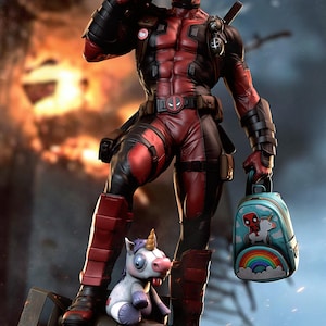 Könnte beinhalten: Eine detaillierte Deadpool-Actionfigur in einem rot-schwarzen taktischen Anzug, die auf einer Bombe steht. Die Figur hält einen kleinen hellblauen Rucksack mit einem Motiv von Deadpool auf einem Einhorn über einem Regenbogen, daneben ein Einhorn-Plüschtier.