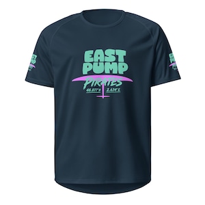 Peut inclure: Un t-shirt bleu marine à manches courtes avec un motif sur la poitrine et les manches. Le motif central affiche le texte EAST PUMP en vert clair, PIRATES en vert clair, et les coordonnées 48.877°N 2.634°E en blanc avec une icône rose.