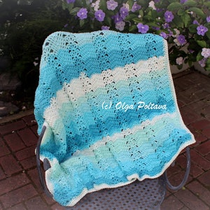 May include: A handmade crochet blanket in shades of blue and white, draped over a chair. The blanket features a wavy pattern and is made of soft yarn. The image includes the text "(c) Olga Poltava".