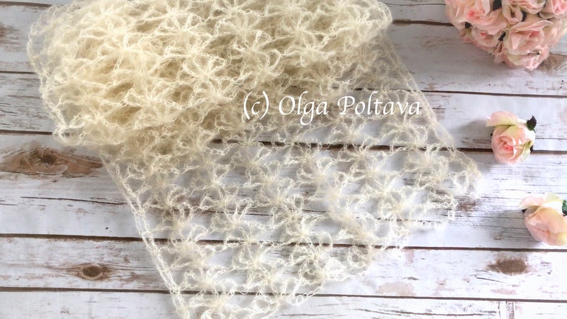 May include: A delicate, off-white crocheted shawl with a lacy, floral pattern. The shawl is laid out on a light wood surface. (c) Olga Poltava