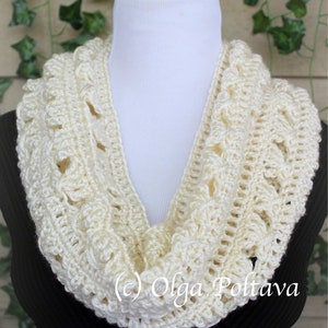 May include: A cream-colored crochet infinity scarf featuring a textured, repeating pattern of raised stitches and openwork loops. The scarf is draped around a white mannequin neck form. The text (c) Olga Poltava is visible on the lower section.