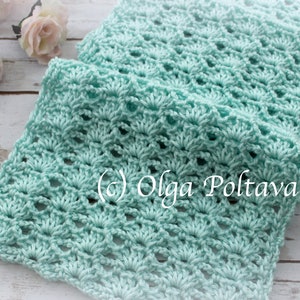 May include: A light blue crocheted scarf with a delicate, lacy pattern. The scarf is folded in half and lying on a white wooden surface. (c) Olga Poltava