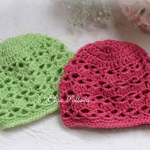Könnte beinhalten: Zwei gehäkelte Mützen, eine grüne und eine rosa, mit einem Spitzenmuster. Die Mützen sind mit einem zarten Stich gearbeitet und haben einen weichen, femininen Look.